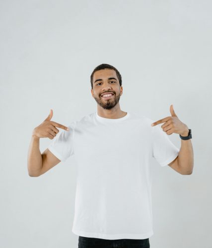 Confident man smiling and pointing at his white shirt with copy space.